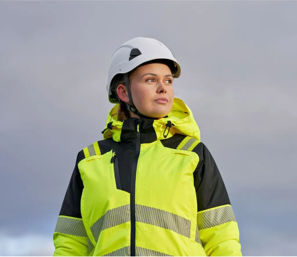 Woman wearing yellow hi-vis jacket and white hard hat outdoors