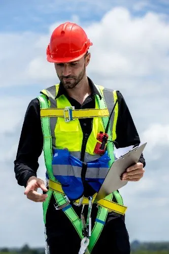 Construction worker in red hard hat and safety vest reviewing clipboard