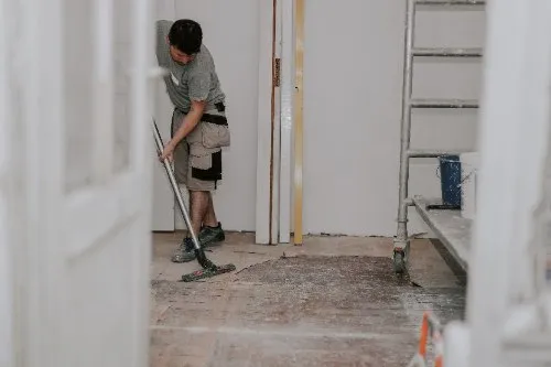 Worker mopping dusty floor during interior home renovation