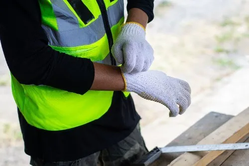 Construction worker in hi-vis vest putting on protective work gloves