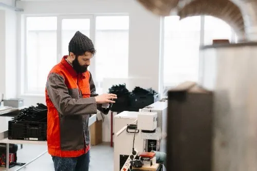 Tradesman in orange vest working with equipment in workshop