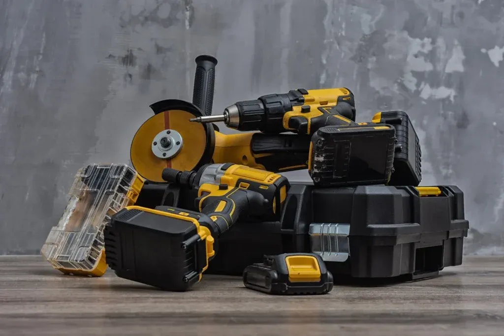 Yellow and black cordless power tools and cases on wood surface
